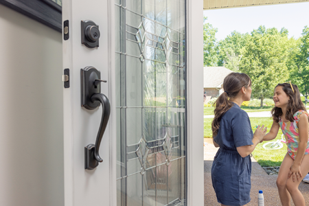 Front door with handleset in the foreground and a mother and her daughter in the background.