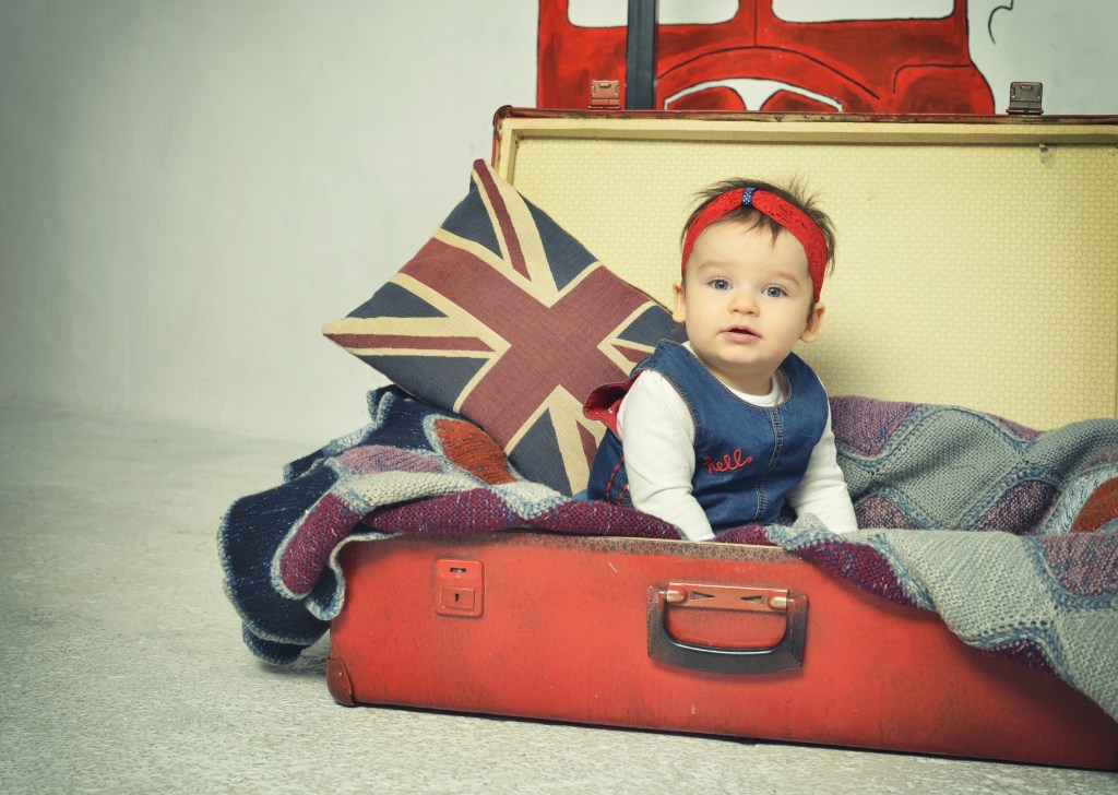 Cute Baby girl sitting in old vintage suitcase with British flag throw pillow