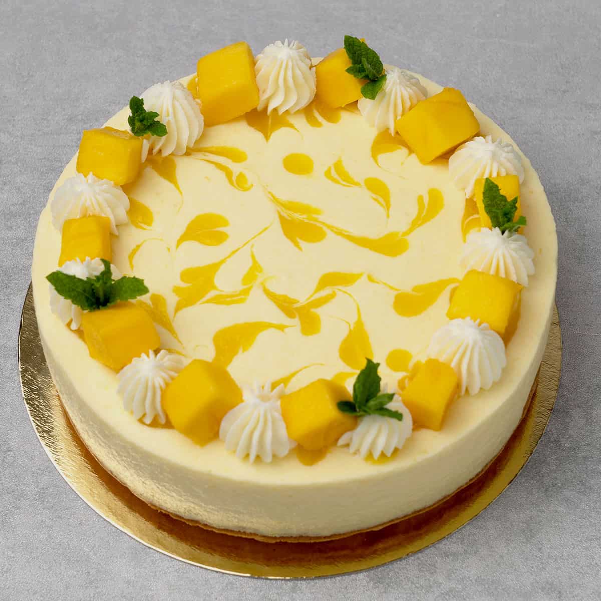 Mango mousse cake on a gold paper plate.