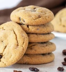 A stack of cookies surrounded by raisins.