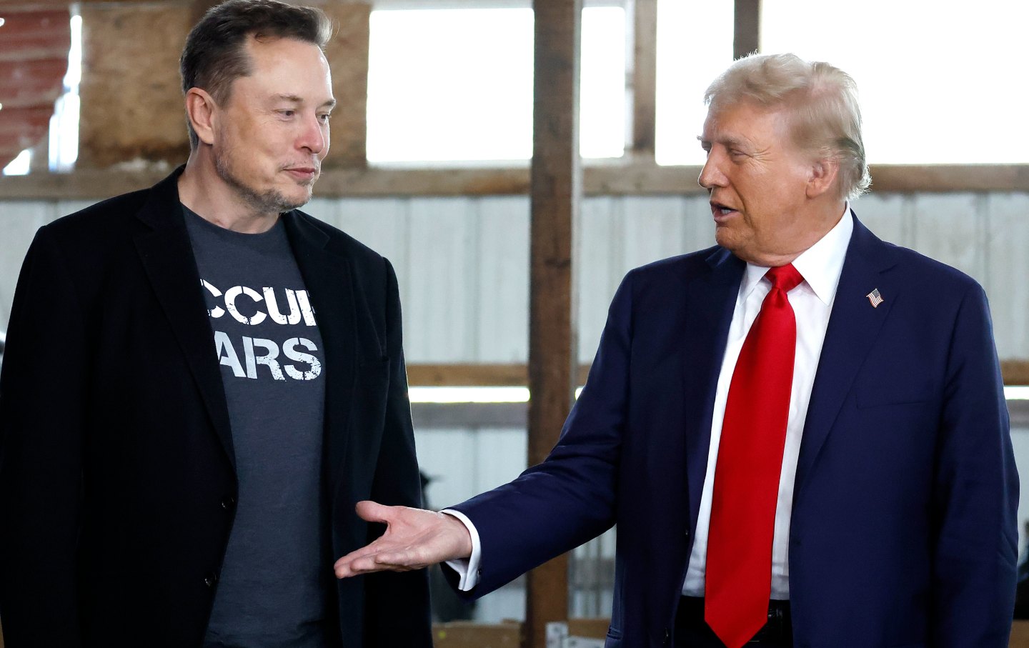 Elon Musk and Donald Trump look at one another.