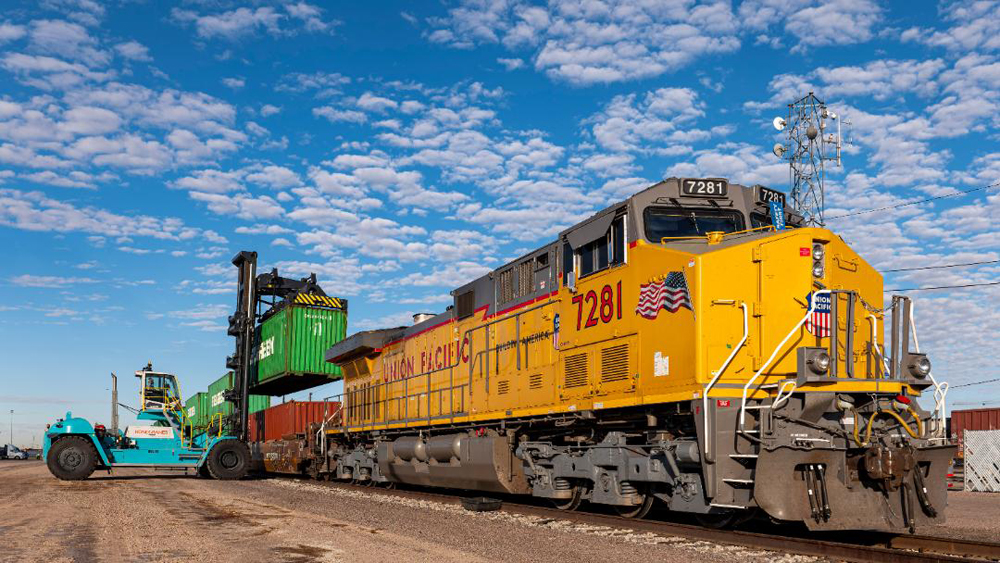 Yellow locomotive with stack cars being loaded