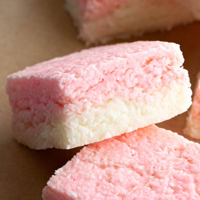 A large square of pink and white coconut ice on a light brown background.