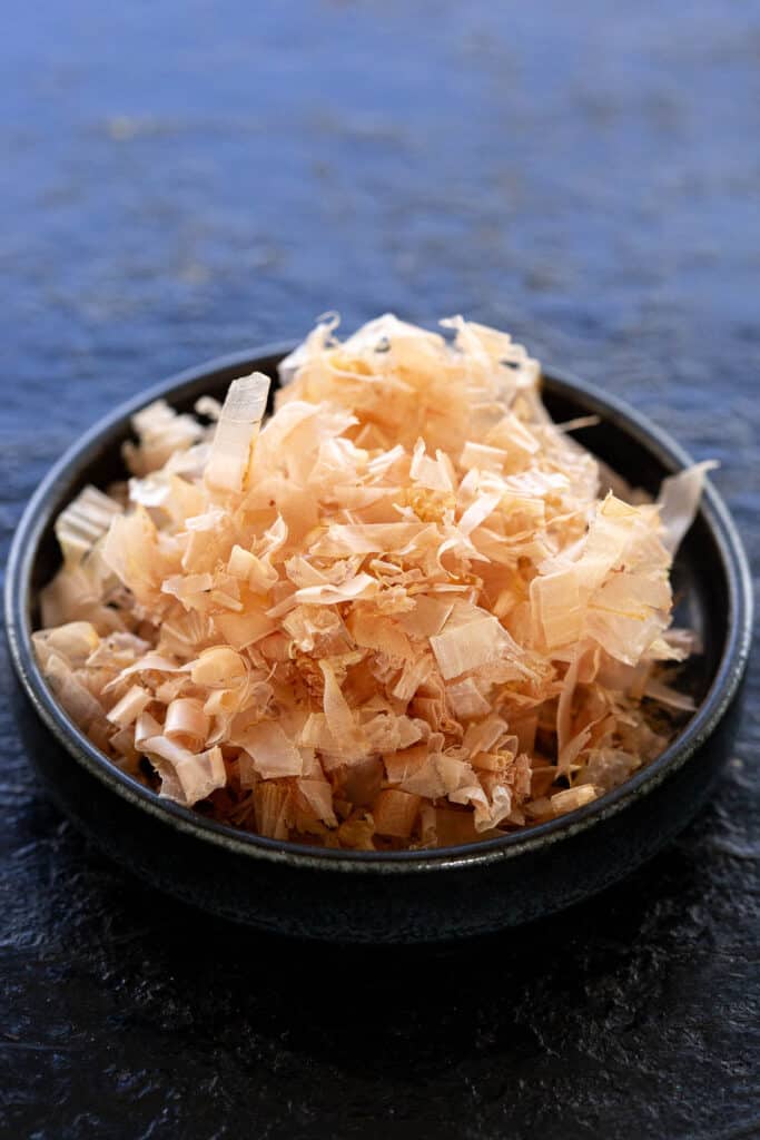 Loose katsuobushi flakes in a small black bowl.