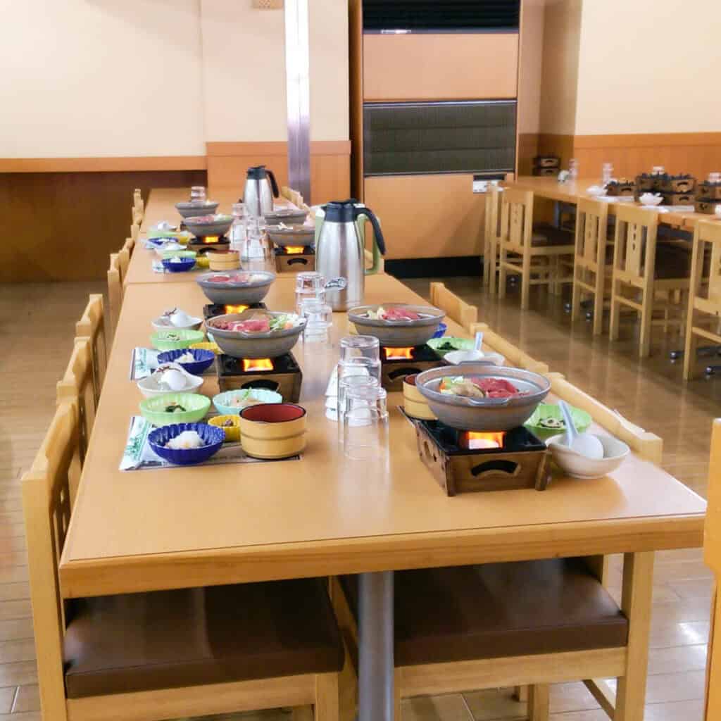 Table filled with individual sukiyaki stations.