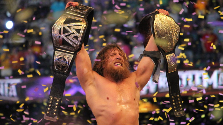 Daniel Bryan holding two belts