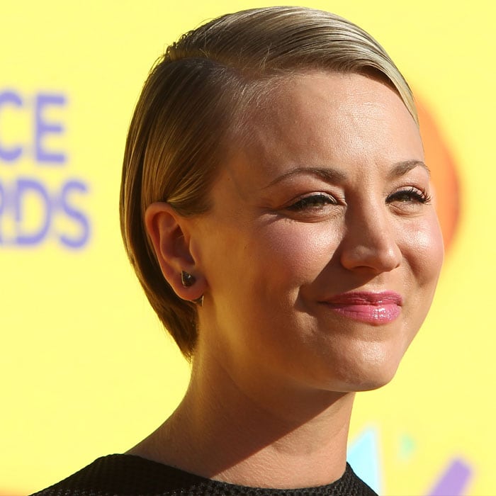 Kaley Cuoco smiles through the sunshine, fighting the glare as she poses on the orange carpet at the 2015 Kids' Choice Awards