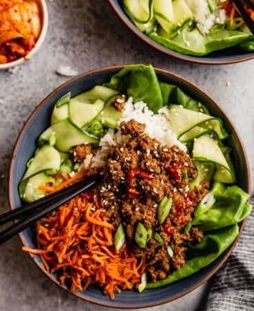 blue bowls filled with ground beef over rice, carrots and cucumbers